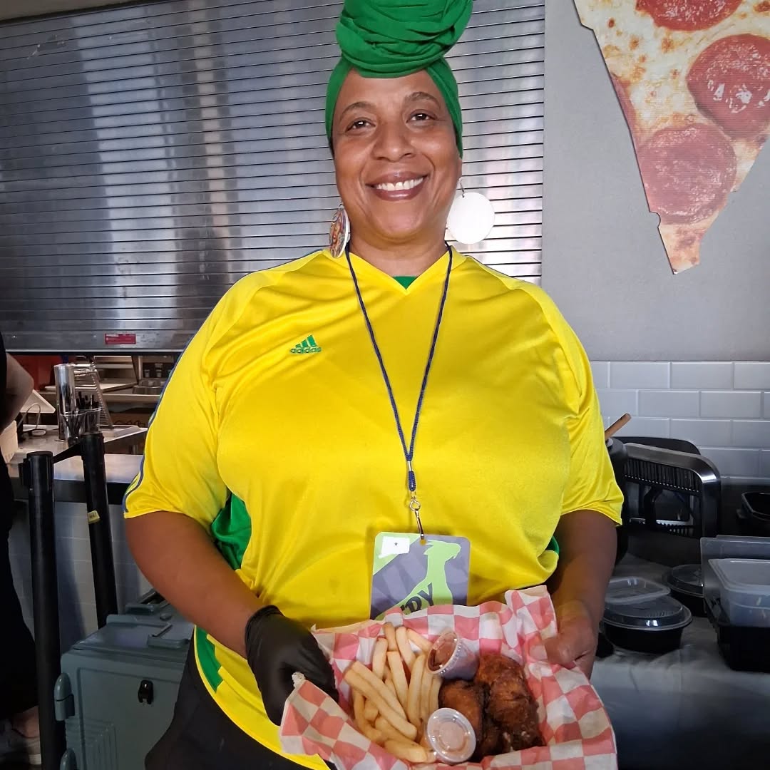 Chef Izolda Miranda at a food truck event, smiling while holding a basket of food